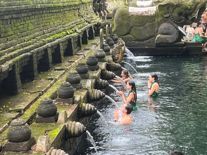 people getting a purifying batj at Pura Tirta Empul fountain