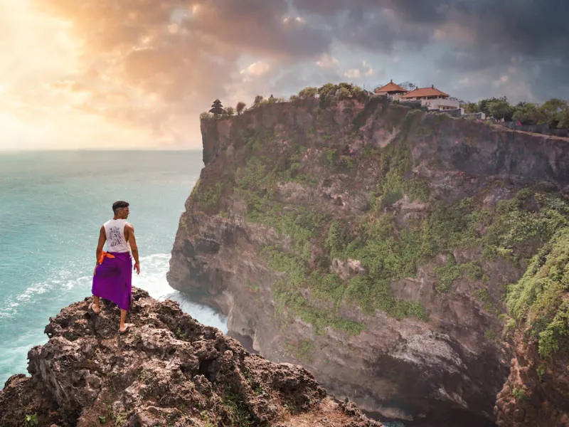 a man contemplating the Uluwatu Temple from the distance